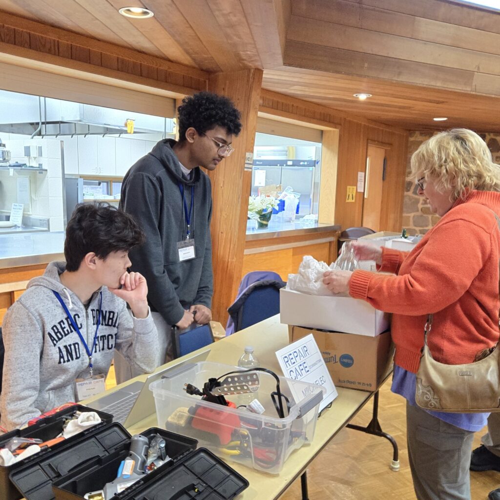 Repair coaches listen to a visitor with item for repair at Repair Cafe Downingtown.